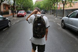 teenager on street holding head